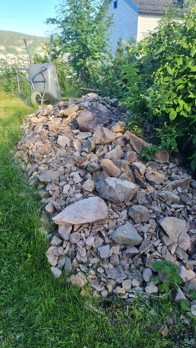 Frakte (trillebår) ca 0,6 kbm steinmasse ca 75 m ned til vei